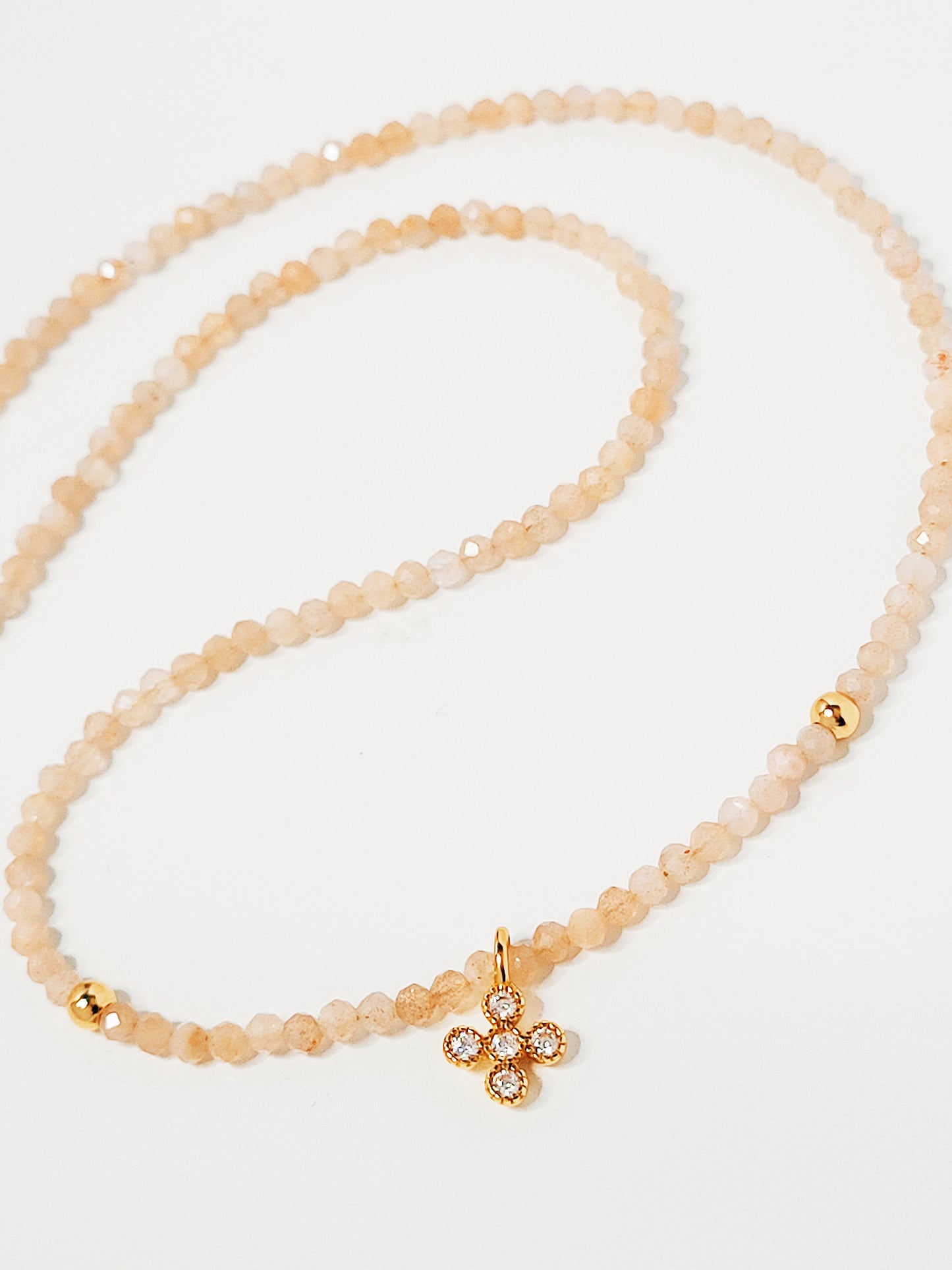 Faceted sunstone bead choker with a gold clover pendant that’s two-sided, showing gold on one side and zircon embellishments on the other.