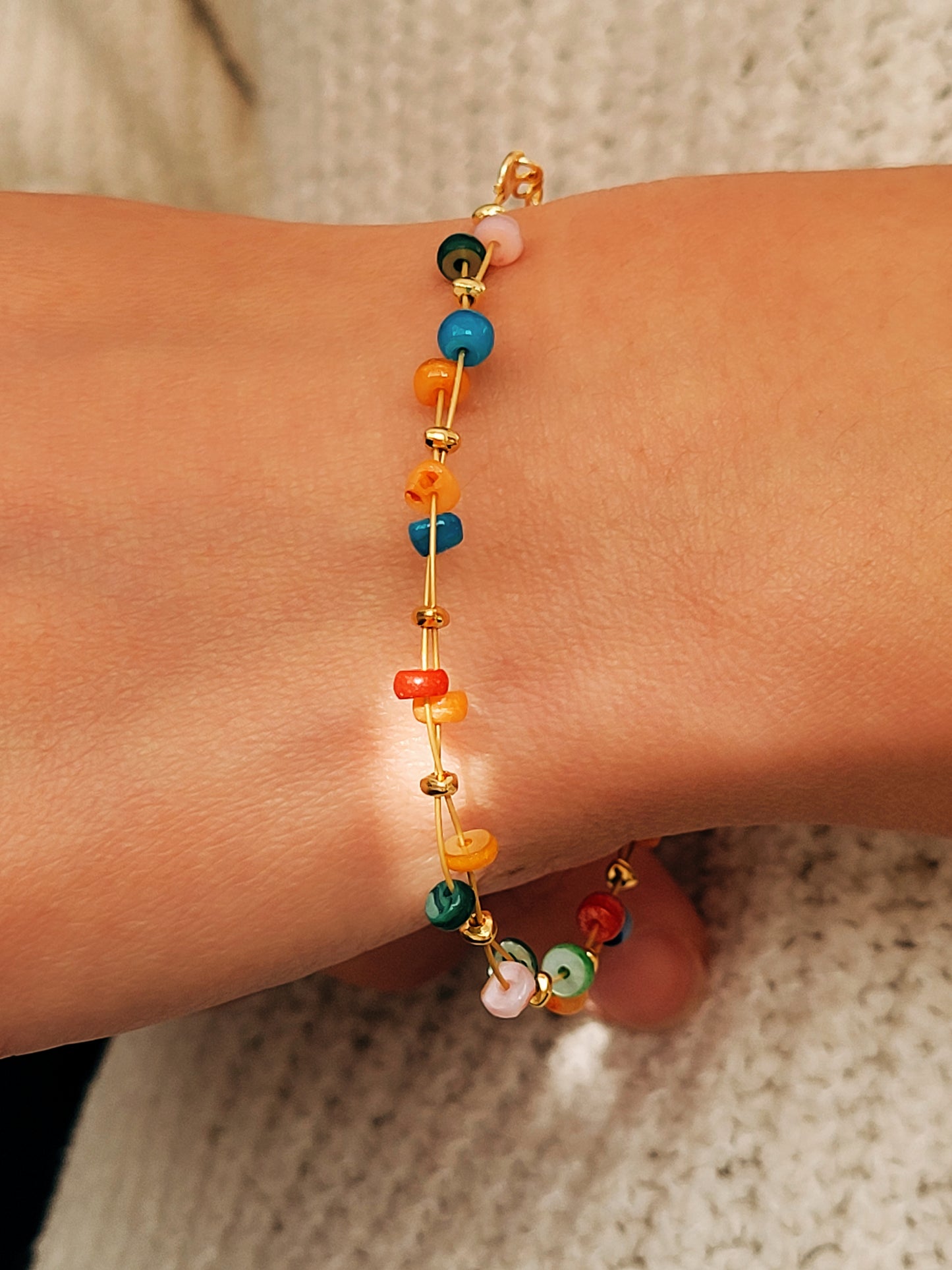 Onyx beaded bracelet with gold accent on a wrist with a neutral background