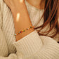 Close-up of a woman wearing a colorful beaded onyx gemstone bracelet on a beige sweater.