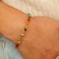 Close up of a woman wearing colorful gemstone beaded bracelet with a minimalist outfit