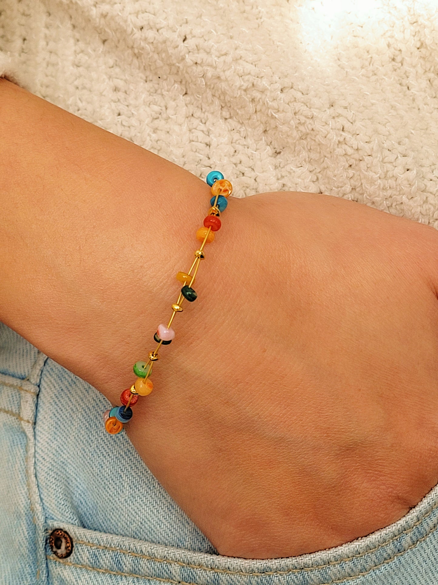 Close up of a woman wearing colorful gemstone beaded bracelet with a minimalist outfit