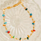 Gold bracelet with colorful beads on a textured glass surface