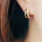 A woman wearing gold double huggie hoop, designed to hug the earlobe for a chic and modern look.