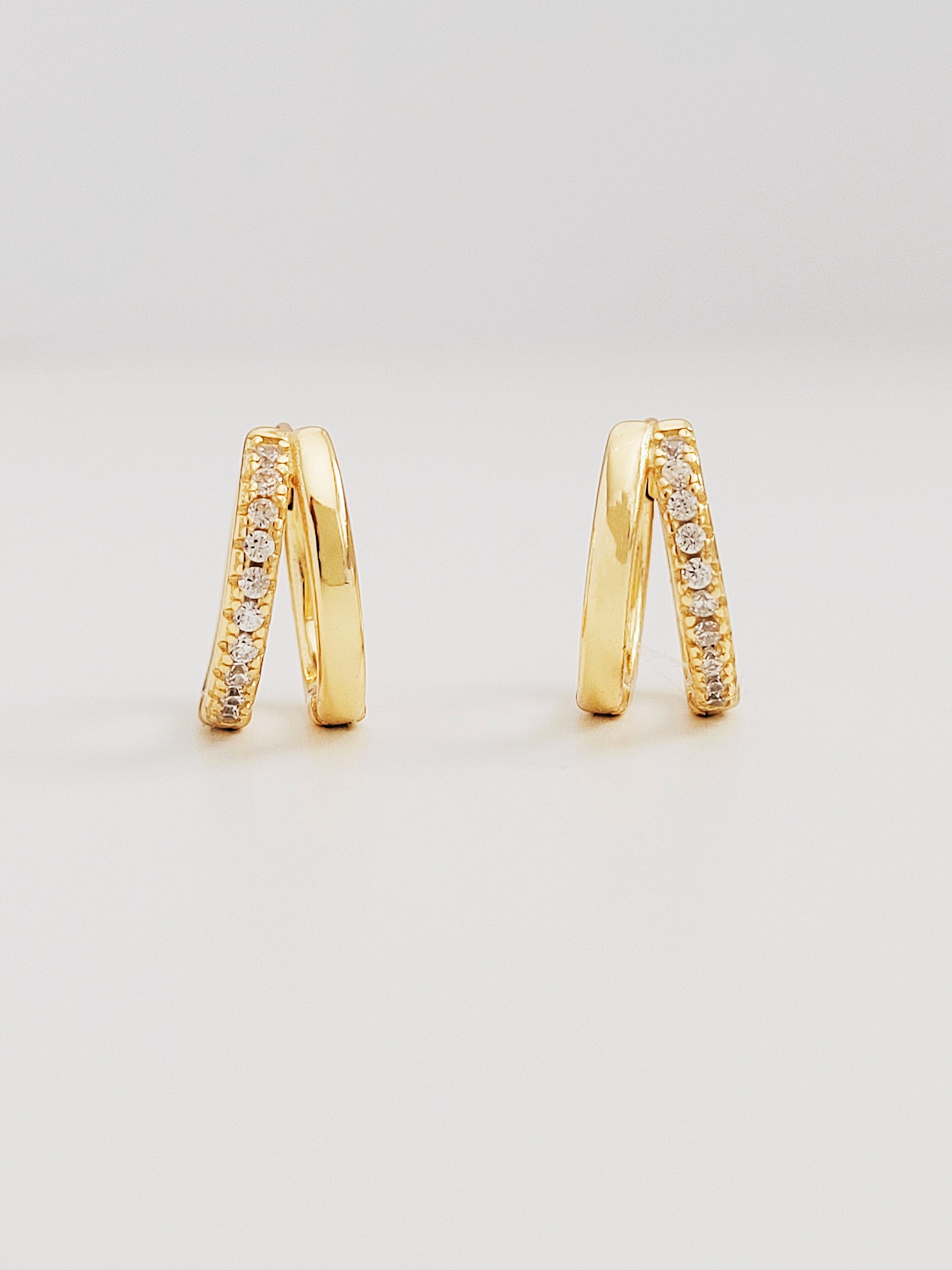 Elegant gold double huggie hoop earrings adorned with sparkling diamond-styled cubic zirconia, perfect for adding a touch of glamour.