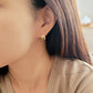 A woman adorned with beautiful gold double huggie hoop earrings, radiating elegance and sophistication.