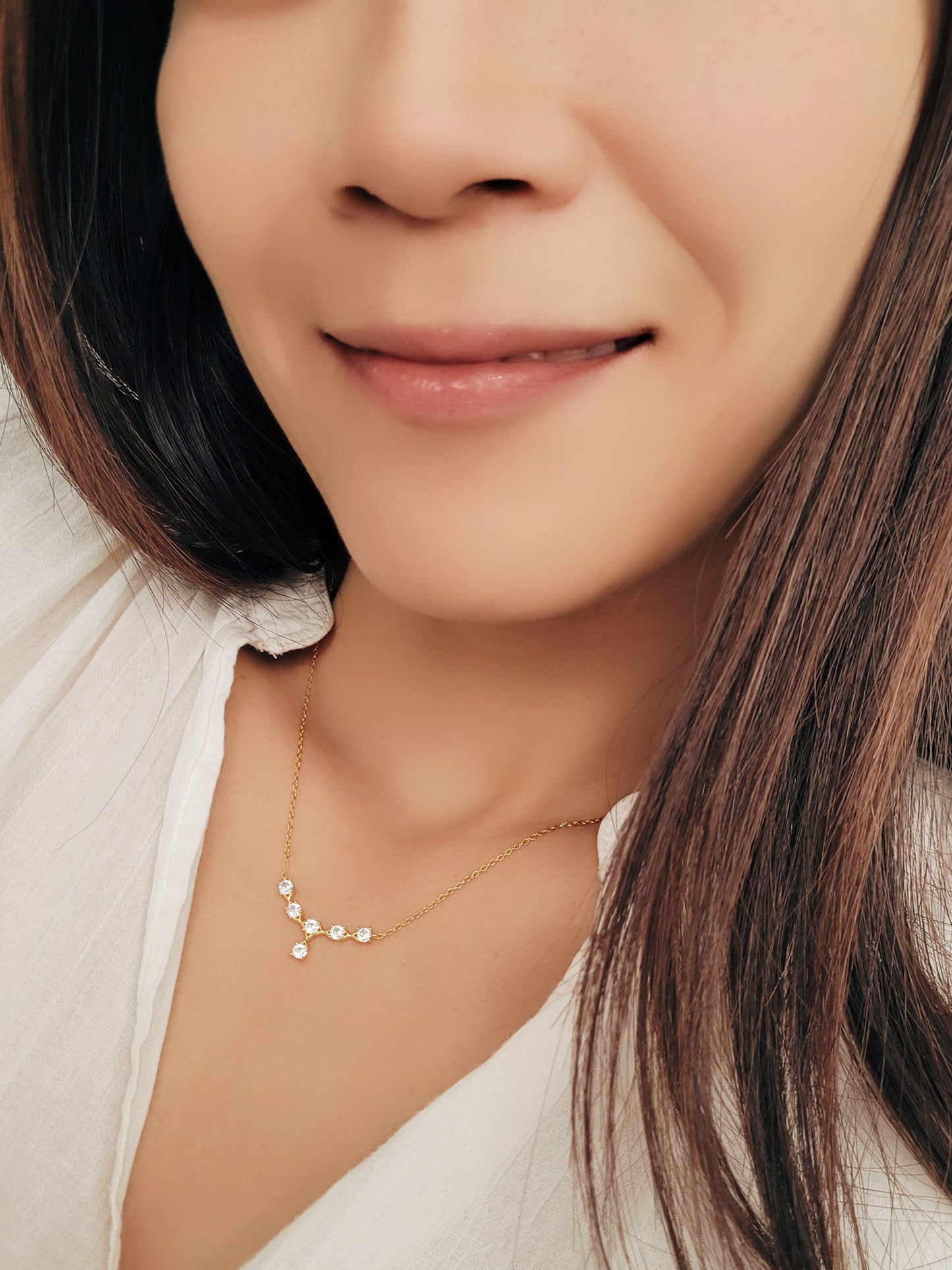 A woman wearing dainty crystal necklace with crown-inspired design, paired with a sleek gold chain for elegant minimalism.