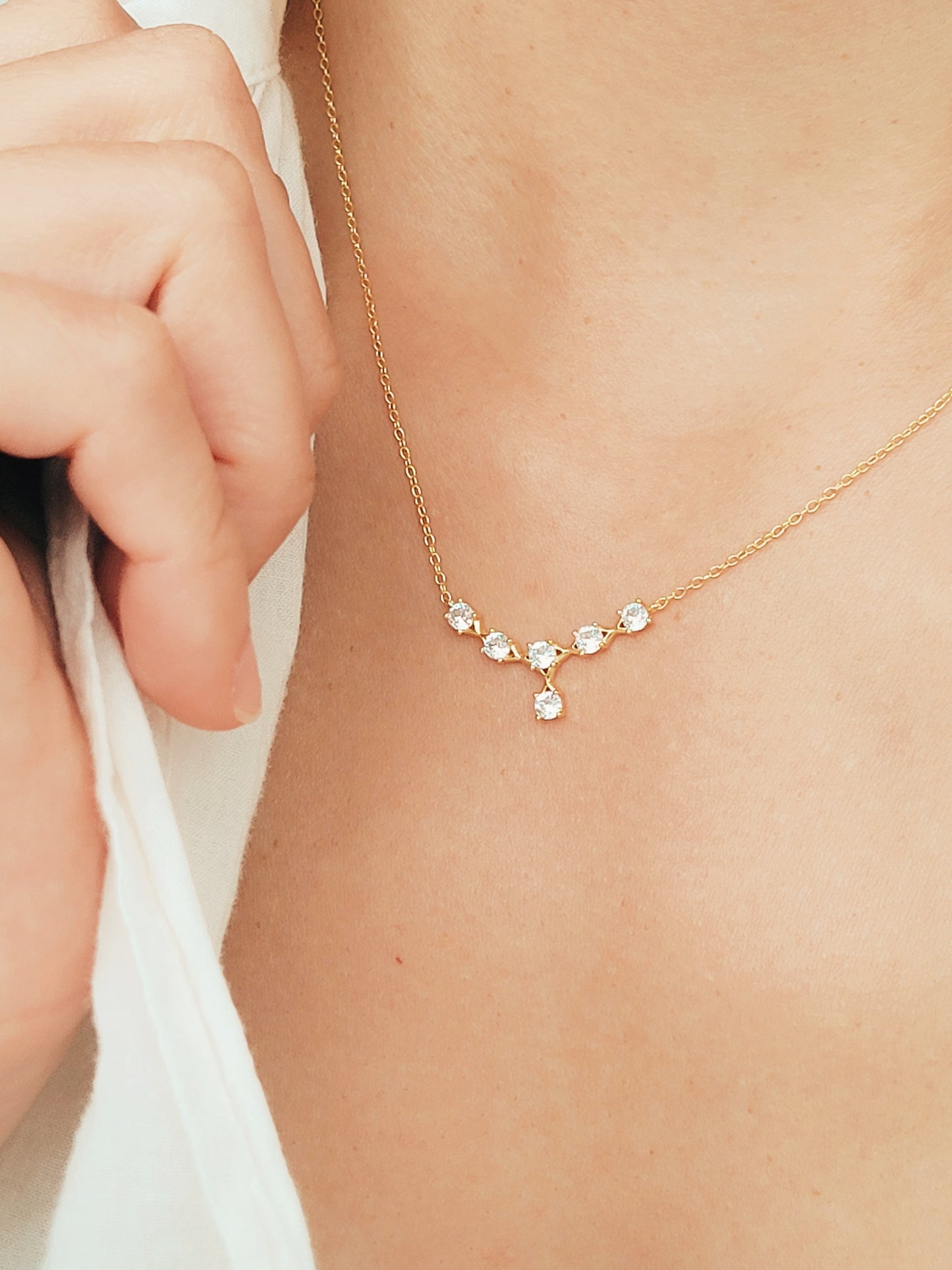 Dainty crystal necklace with crown-inspired design, paired with a sleek gold chain for elegant minimalism.