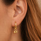 Gold double hoop earrings with small spherical charms worn by a woman, elegant and edgy earrings for everyday wear.