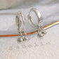 Silver double hoop earrings with small ball charms on a white surface with 'JaBelle' branding, modern and stylish earrings crafted in 925 sterling silver.