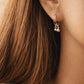 Close-up of a double hoop earring with small dangling beads worn by a woman showcasing soft and minimalist aesthetic outfit.
