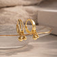 Gold hoop earrings with small spherical charms on a neutral background