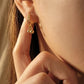 Close-up of a woman wearing gold hoop earrings with small ball charms dangle, dainty jewellery gift for her.