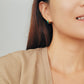 Smiling woman flaunting her colorful Enamel Huggie Hoop earrings, radiating joy and style.