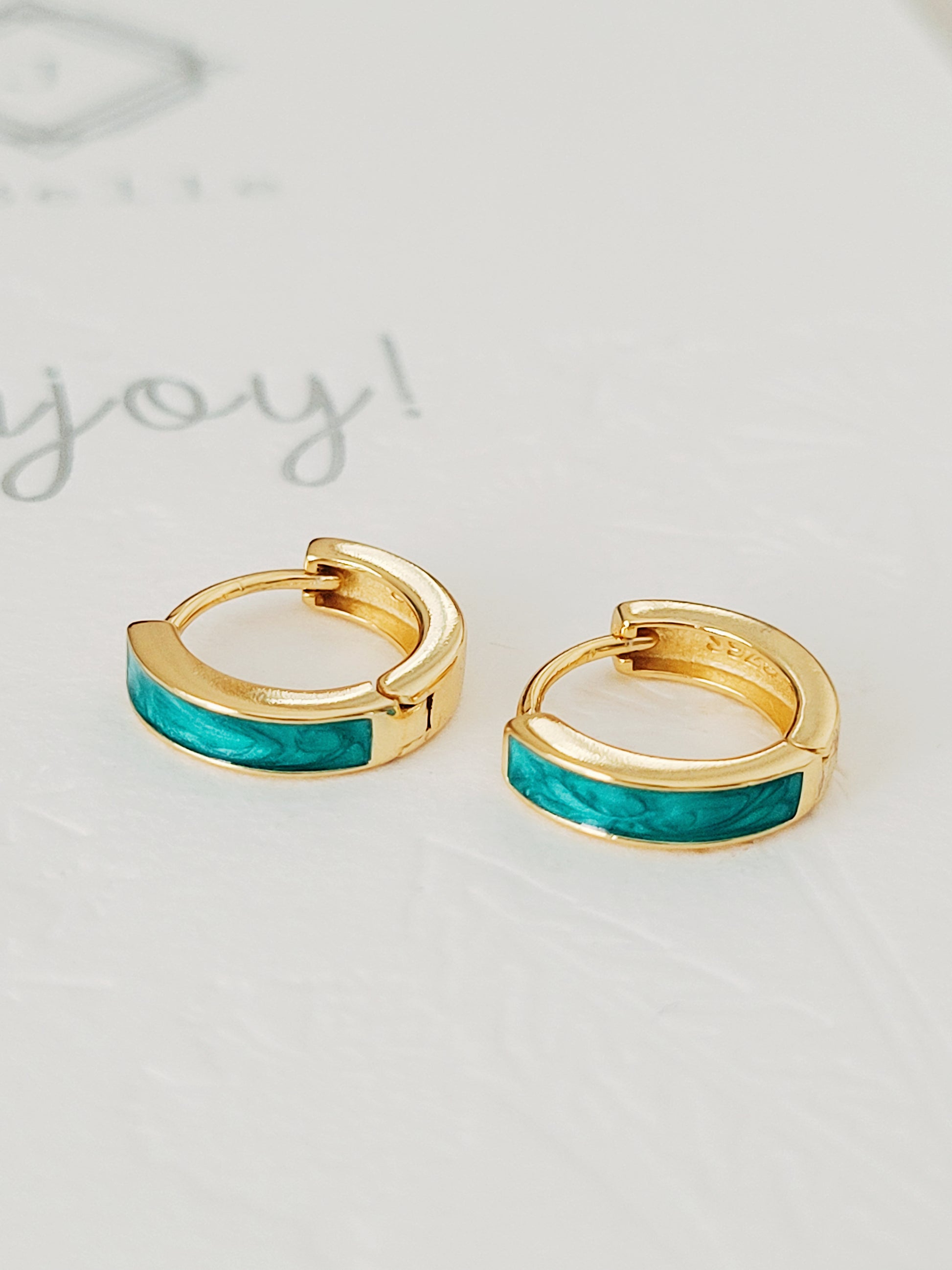 Elegant gold and turquoise green enamel huggie hoop earrings, featuring a chic design that adds flair to your everyday style.