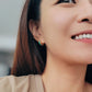 A woman smiles brightly, showcasing her stylish Enamel Huggie Hoop earrings.