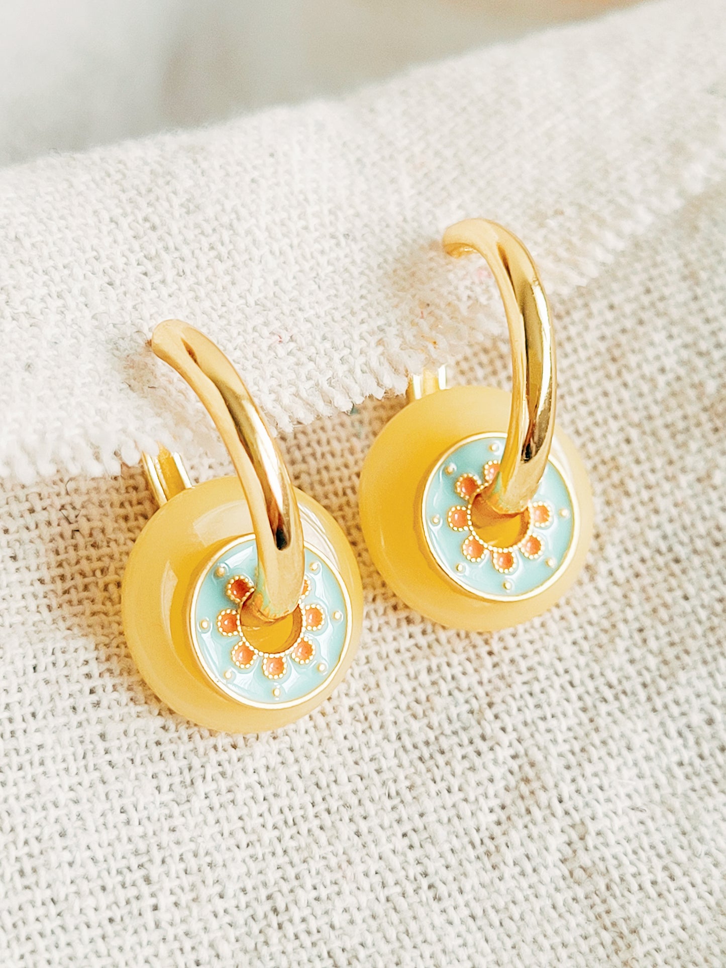 Gold hoop earrings with enamel disc and yellow glass drop, perfect for adding a pop of color.