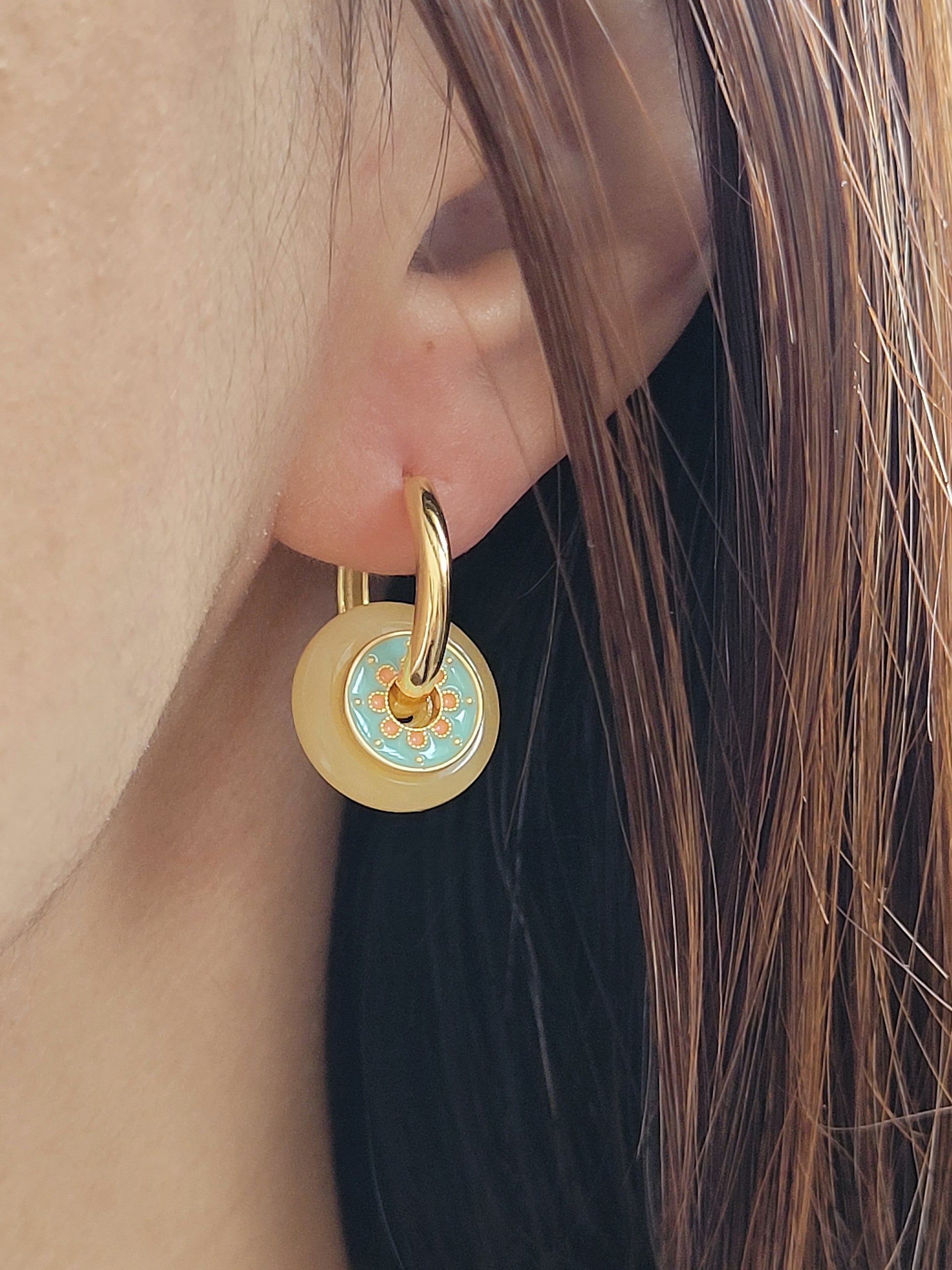 Close up of a woman wearing vintage-inspired enamel disc earrings with yellow glass drop and gold-plated hoops.