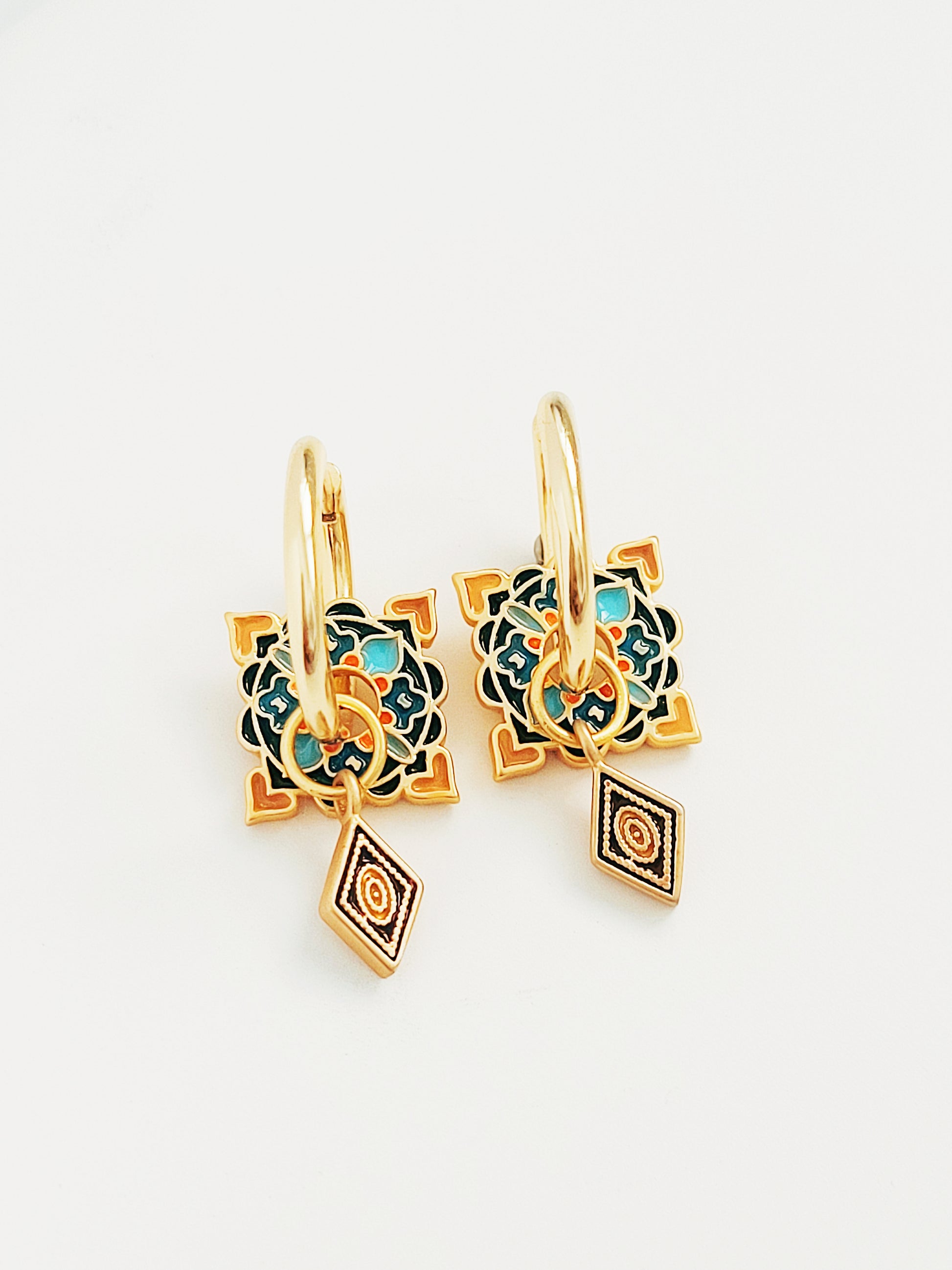 Pair of gold-plated Enamel hoop earrings featuring intricate enamel tile patterns in teal, navy, and orange with dangling diamond-shaped charms.