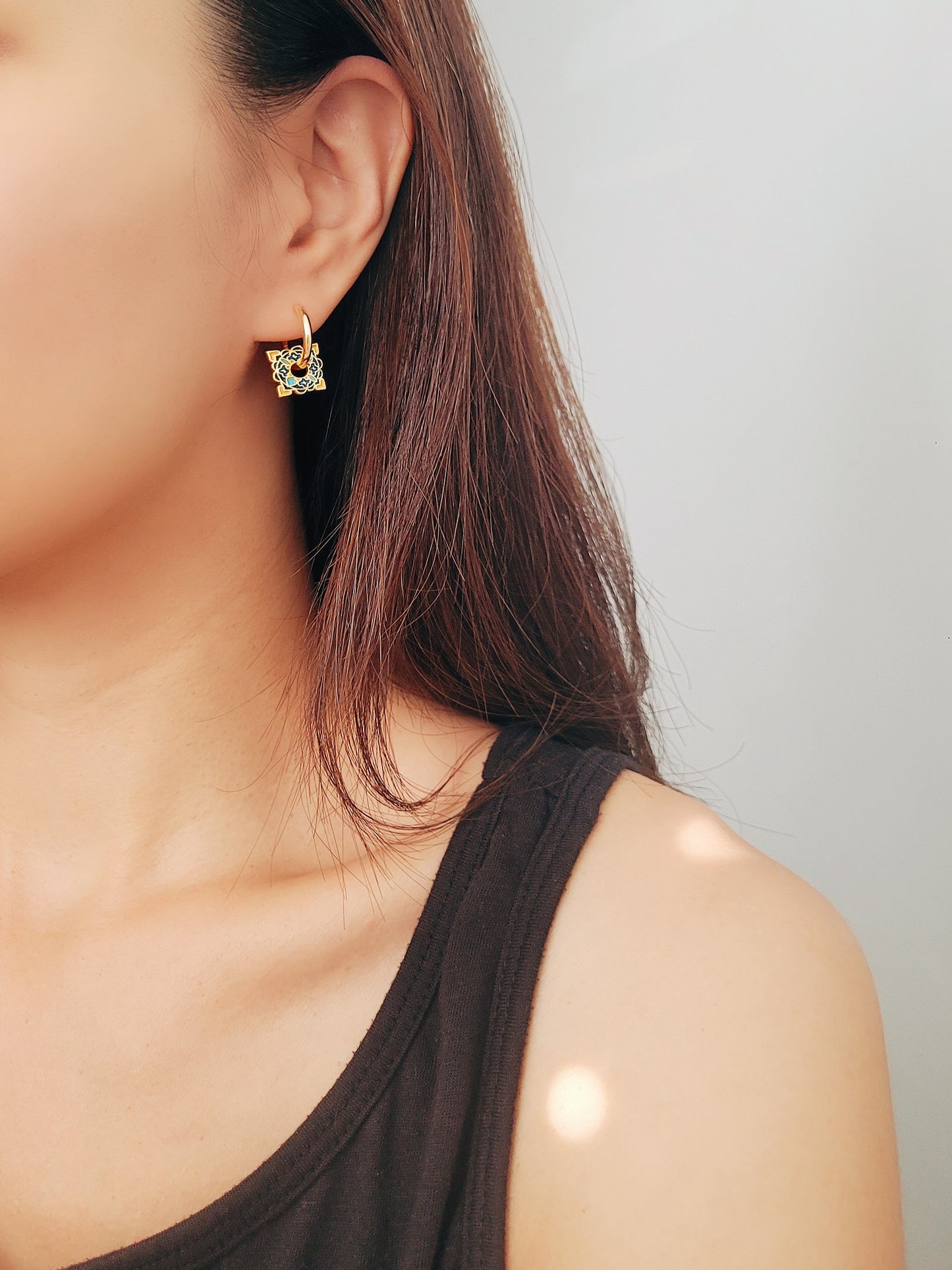 Close-up of elegant tile-inspired Enamel hoop earrings with vibrant geometric enamel designs and gold accents on a woman's ear.