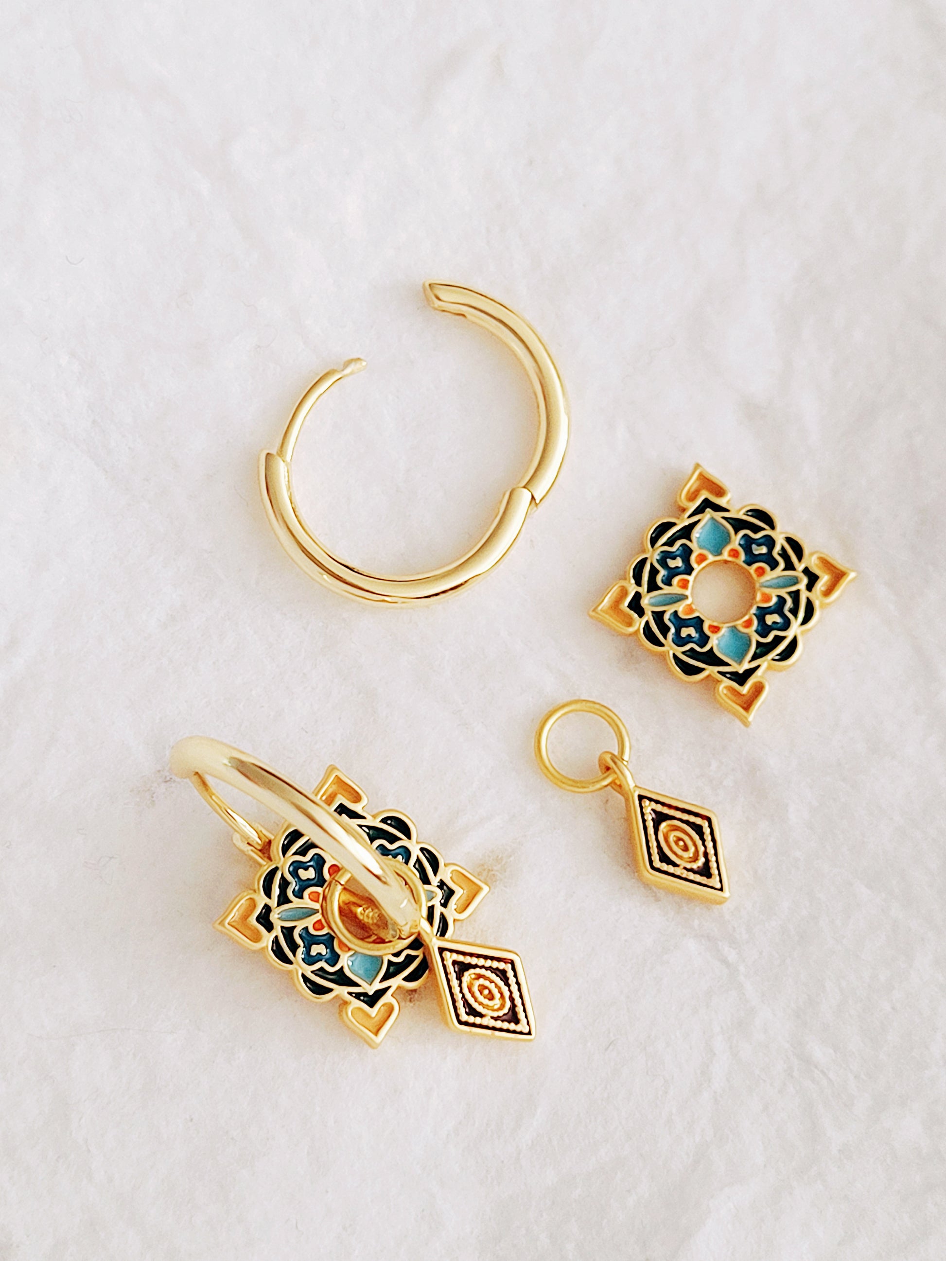 Gold hoops with colorful tile-patterned enamel squares and dangling diamond charms, blending traditional and modern aesthetics.