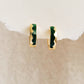 Gold hoop earrings with green enamel on a beige background