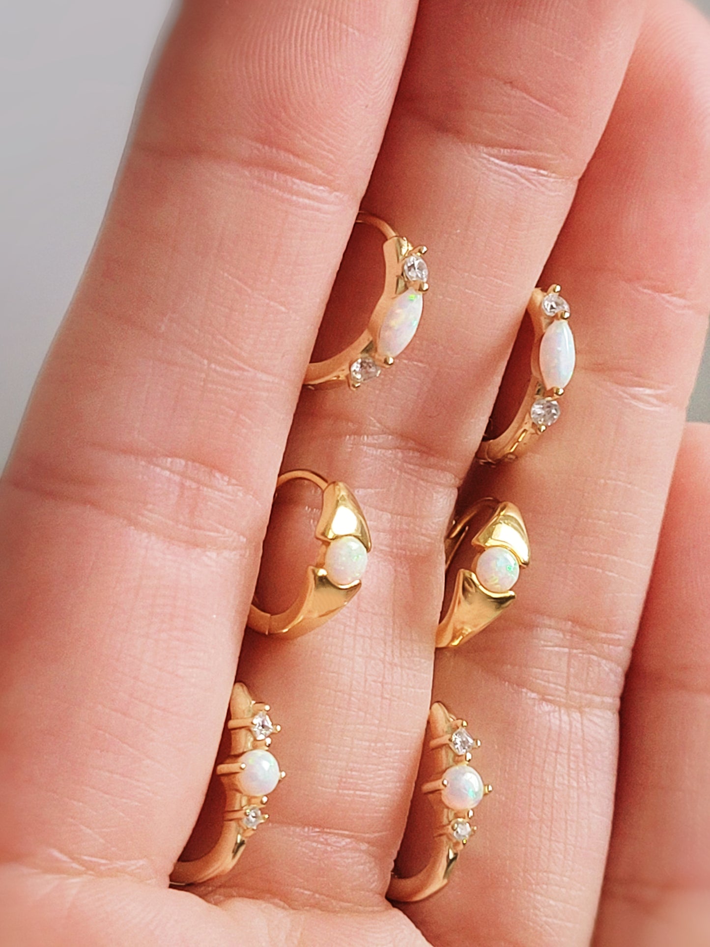 Close-up of opal huggie earrings with a dainty minimalist design. Dainty and elegant opal hoops, ideal as a gift for sisters or minimalist jewelry lovers.