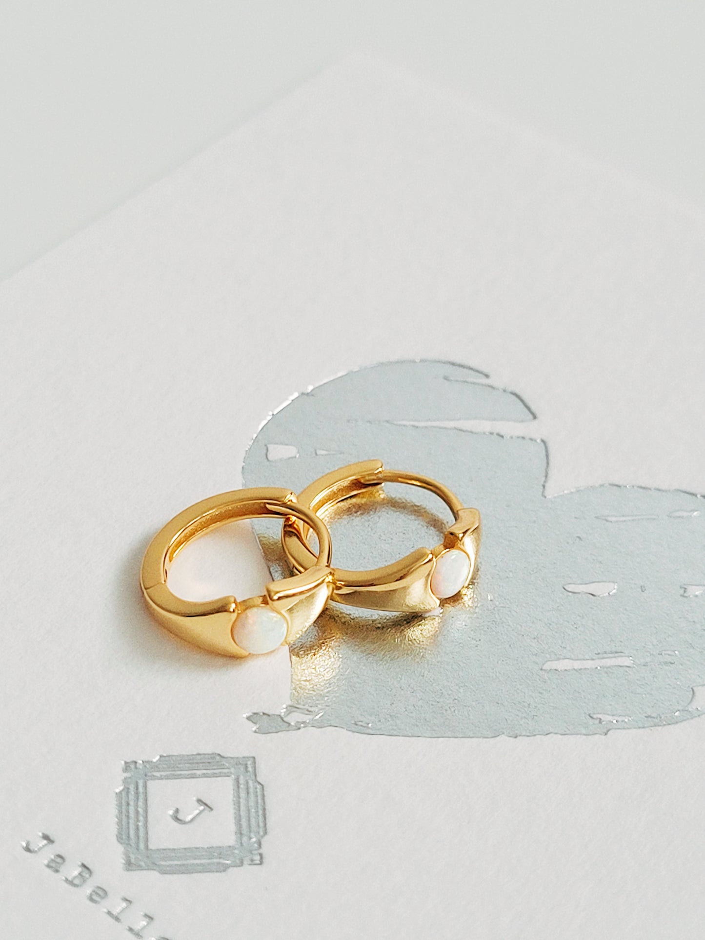 Small gold hoop earrings featuring an evil eye design with a shimmering opal stone centerpiece, perfect for everyday wear. Crafted in 18k gold plated sterling silver, hypoallergenic and comfortable.