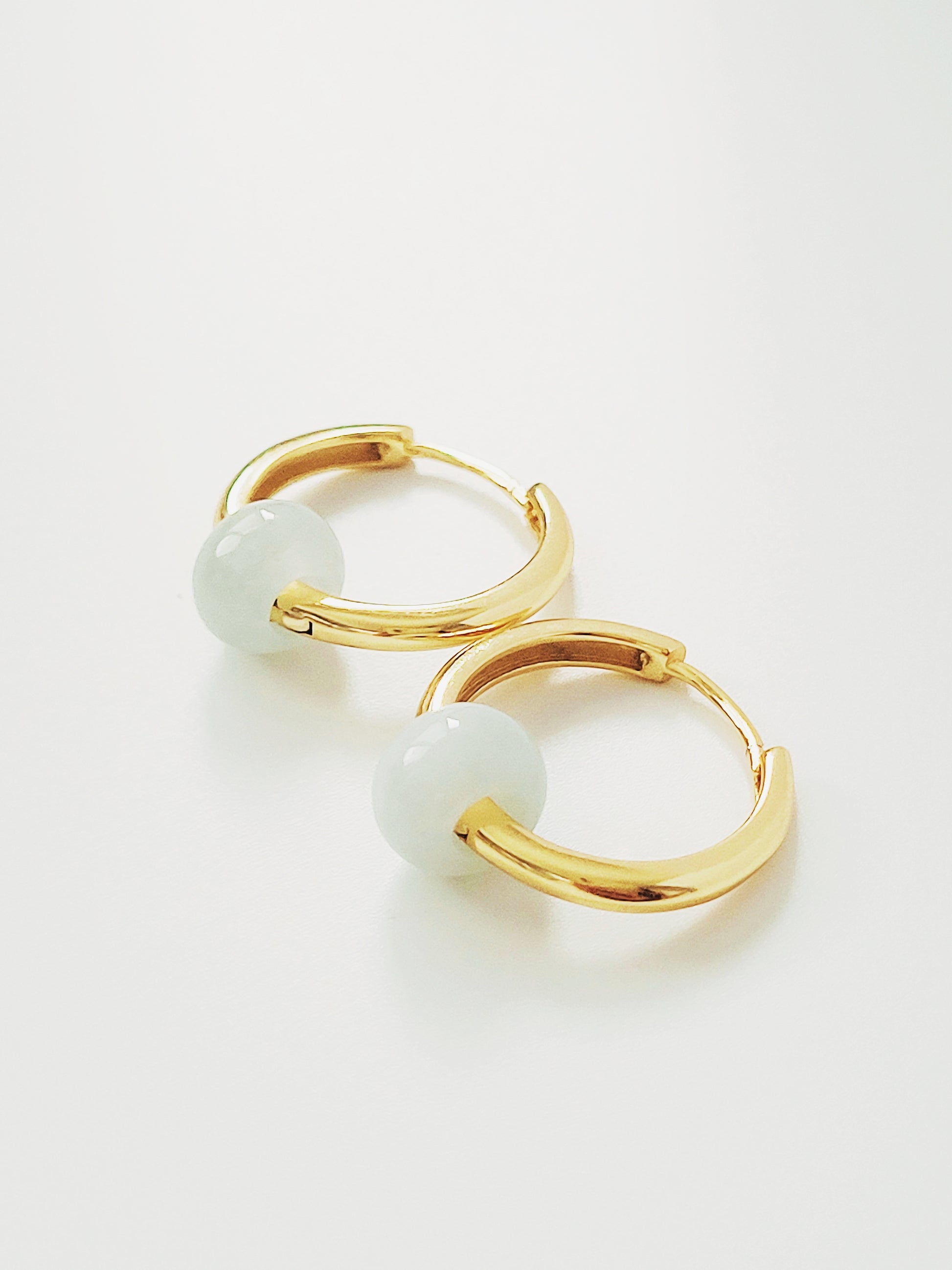 Elegant gold hoop earrings adorned with exquisite pale green jade natural stones, embodying timeless luxury and sophistication.