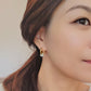 A woman in a cozy white sweater, adorned with stunning 18ct gold jade hoop earrings, radiates elegance and style.