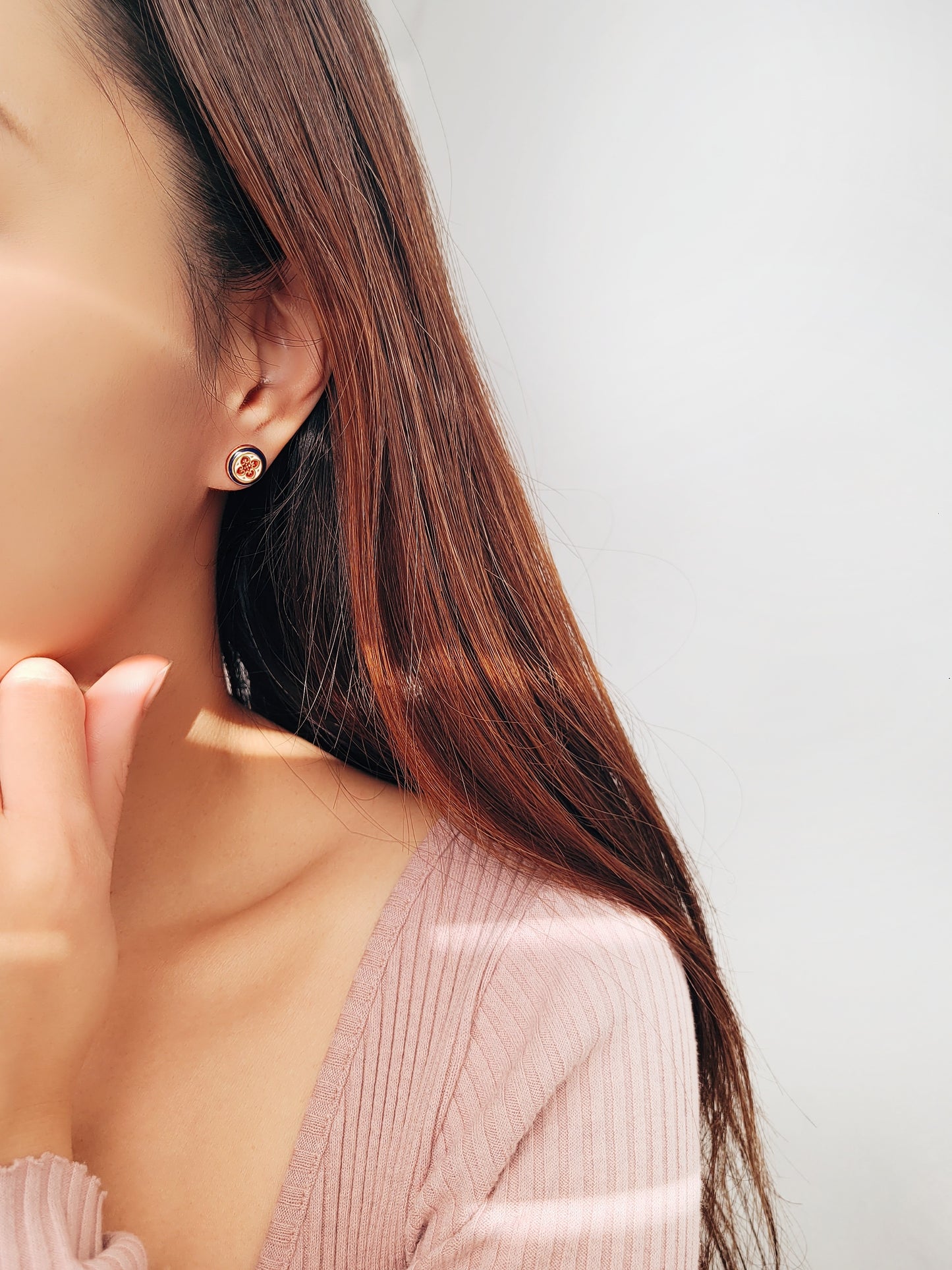 Close-up of a woman's ear wearing a pair of Retro Gothic tile pattern enamel stud earrings in red, blue, and gold. The intricate design features a vintage-style pattern with a bold color combination, creating a striking and elegant look."