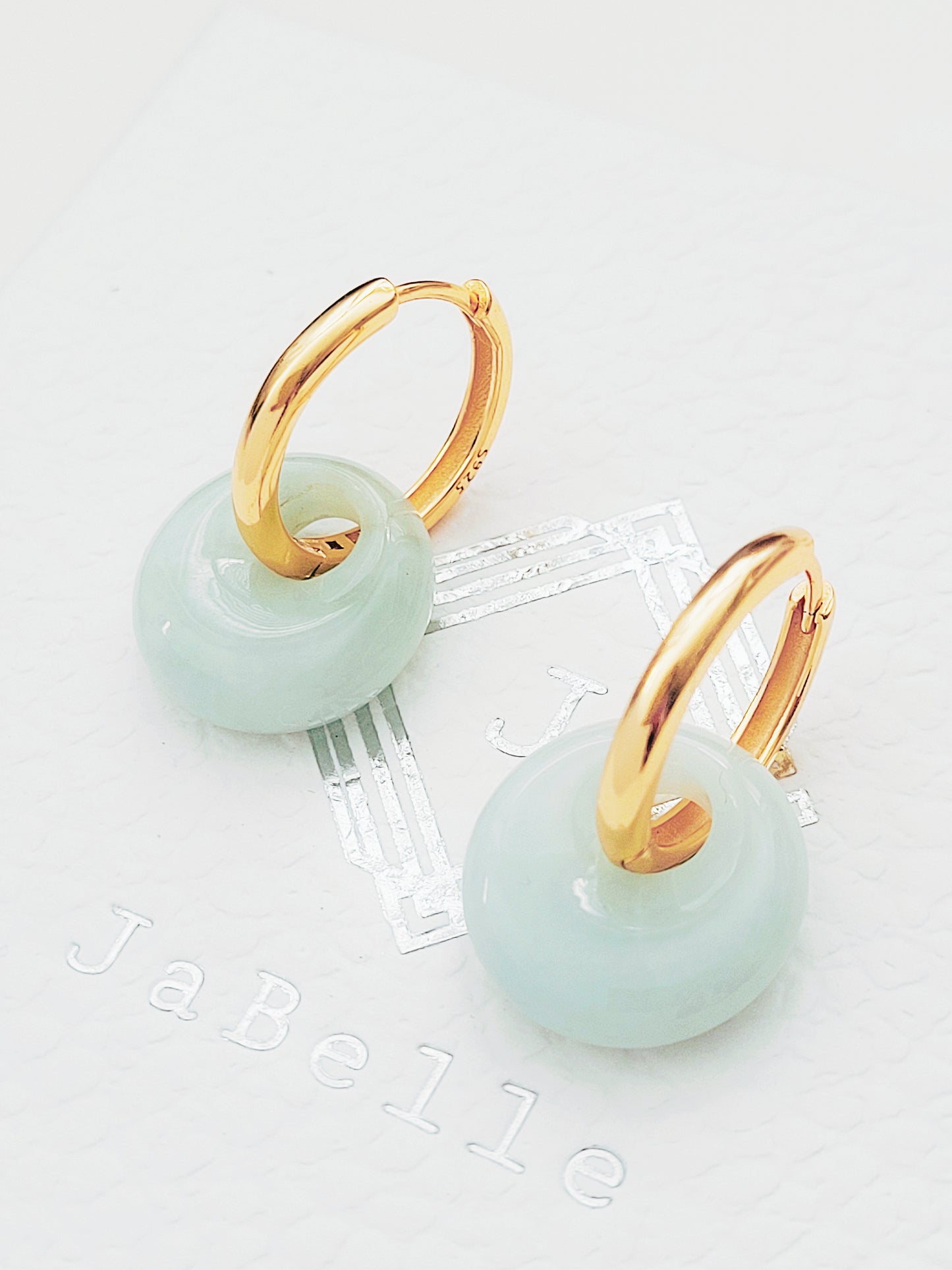 Close-up of jade hoop dangle earrings with nephrite jade drops on gold huggie hoops, perfect for minimalist styles.