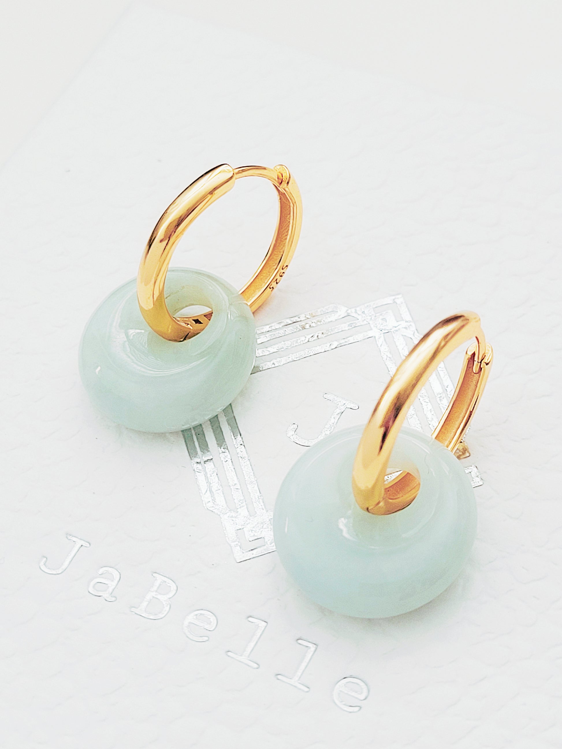 Close-up of jade hoop dangle earrings with nephrite jade drops on gold huggie hoops, perfect for minimalist styles.