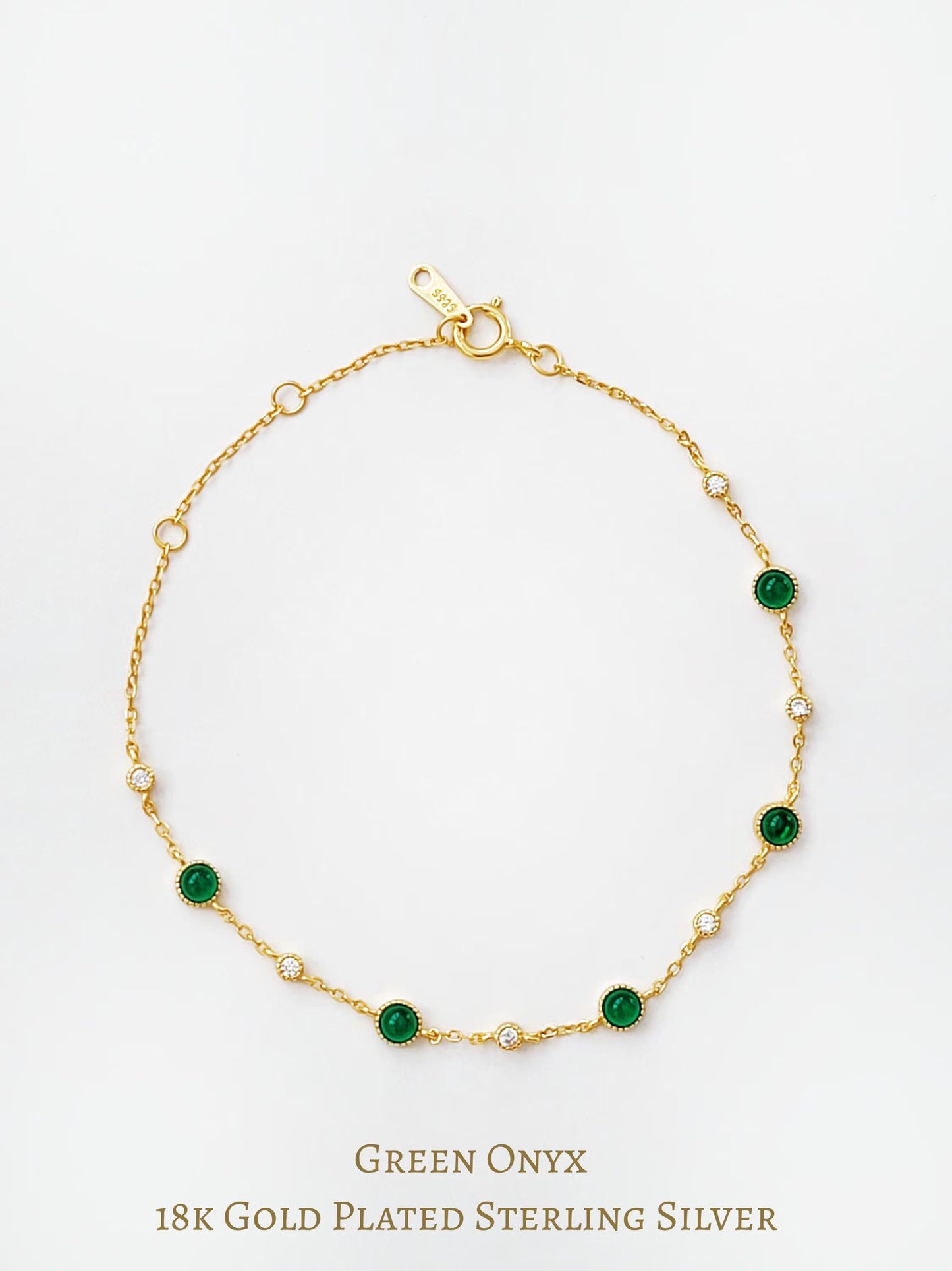 Gold station bracelet with green onyx gemstones and cubic zirconia stones on a white background