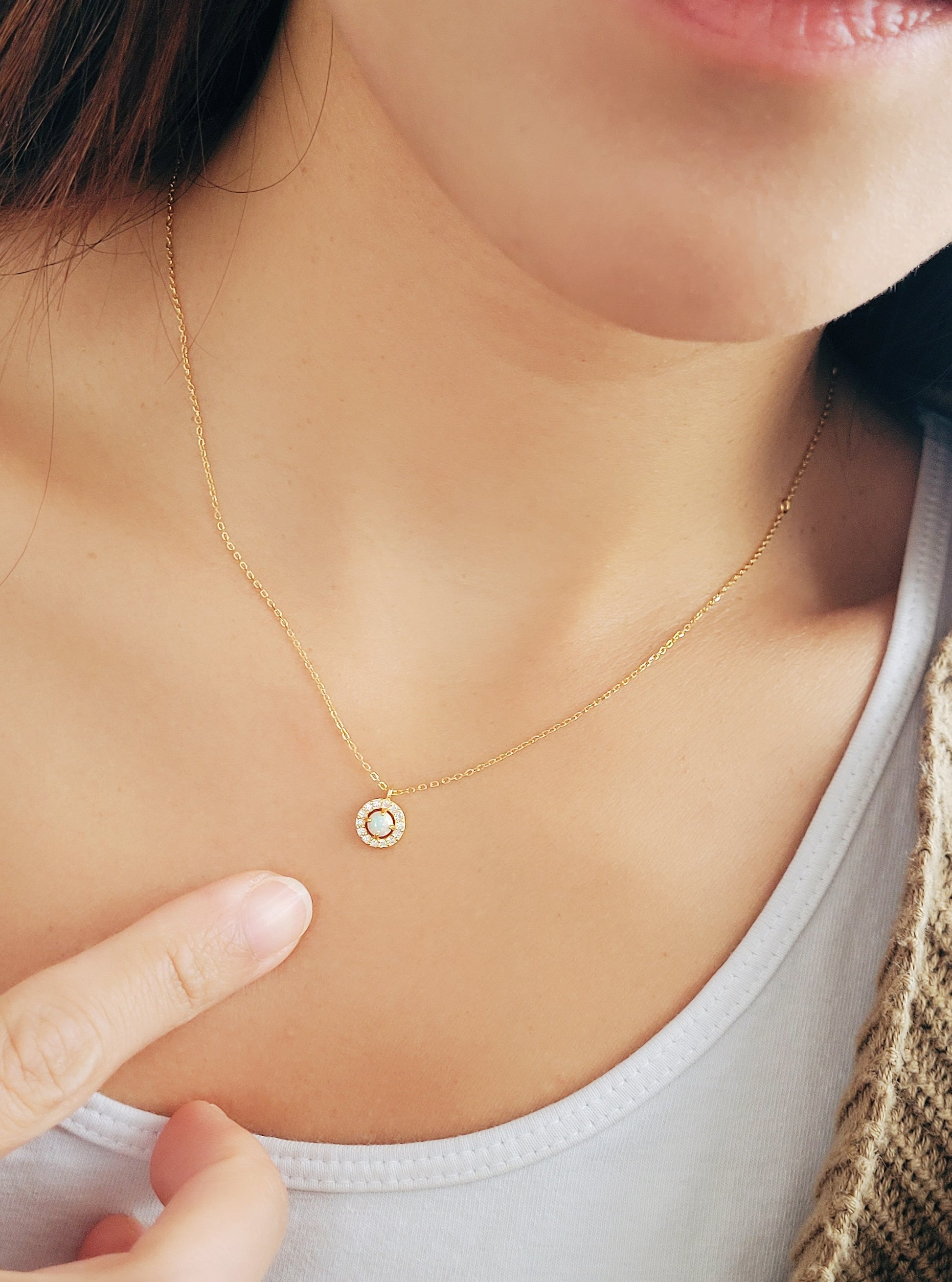 A woman wearing a dainty opal necklace.