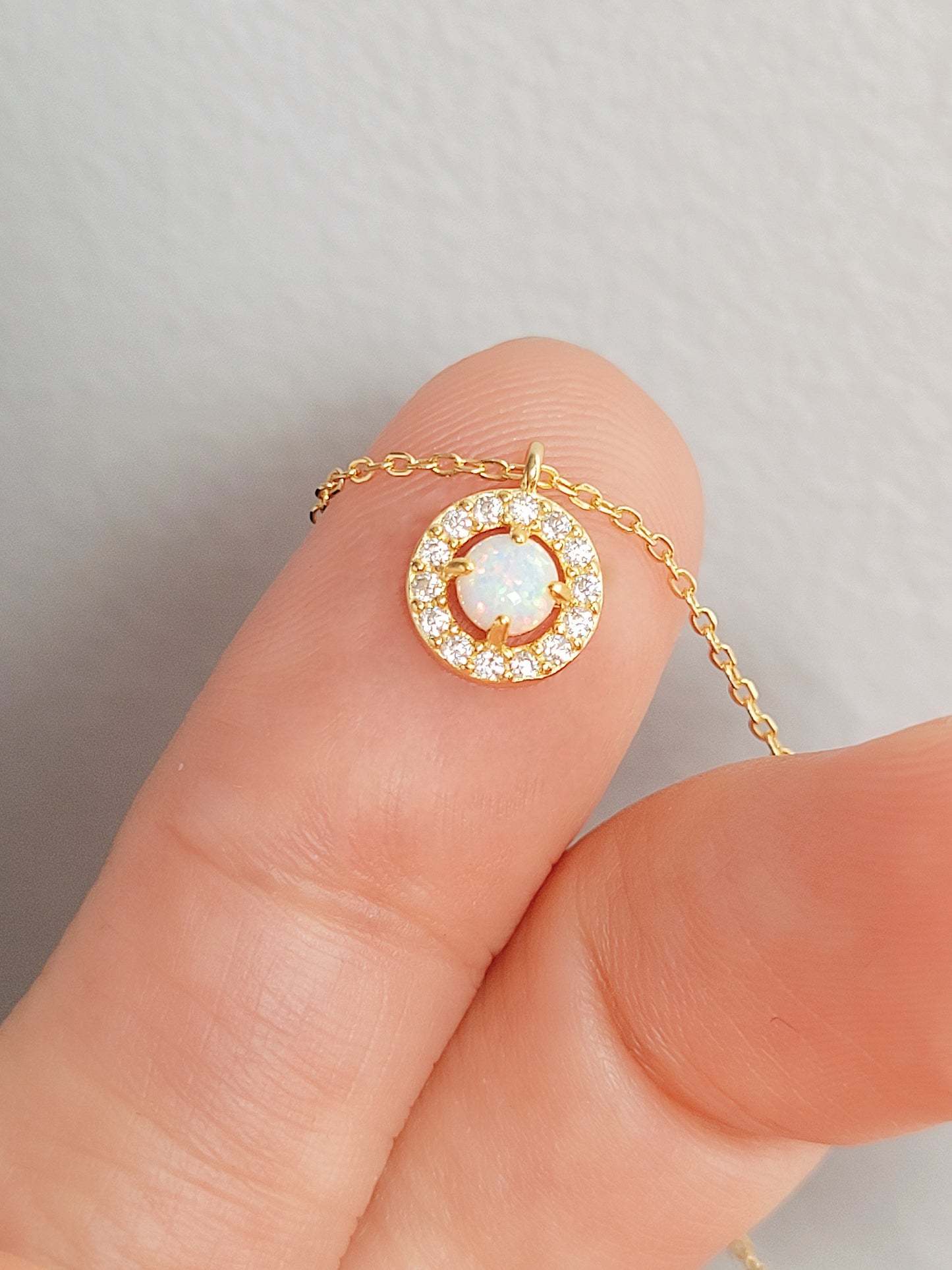 close up of fire opal necklace on a woman's hand.