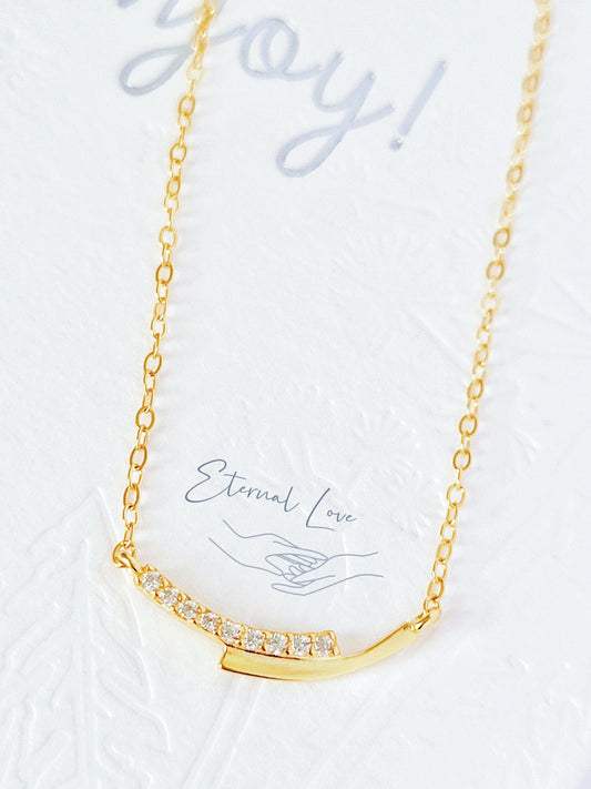 A gold-plated sterling silver necklace with a geometric design, displayed against a white background with the text 'Hand in Hand' and 'Spread love & kindness'.