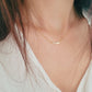 Woman wearing a simple gold bar necklace, dainty and minimalist style.
