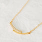 Close up of a simple gold bar necklace with cubic zirconia accents, symbolizes love and unity.