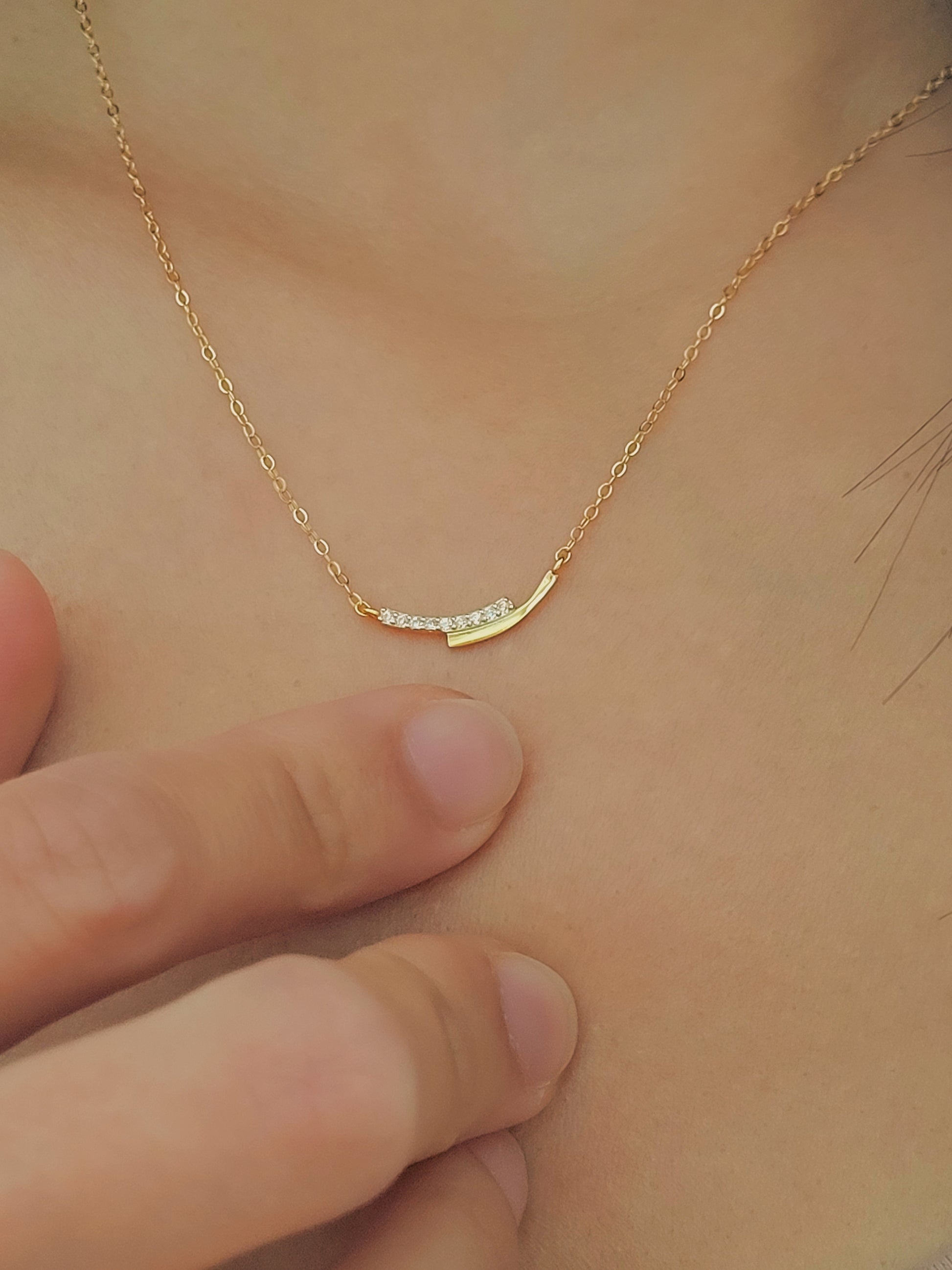 Close up of a lady wearing a gold necklace crafted in gold plated sterling silver with shimmering diamond.