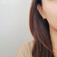 Close-up of a person wearing an orange earring with a plain background