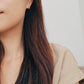 Close-up of a person wearing gold hoop earrings with a neutral background