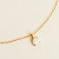 A delicate gold chain necklace featuring a small oval opal pendant in a gold bezel setting, displayed on a clean, light beige background.