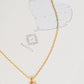 A delicate gold chain necklace with a small opal pendant holding a round, milky white opal gemstone, displayed on a textured white card with a silver heart illustration.