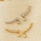 Gold and silver bubble climber earrings displayed together on textured beige fabric, showing the two metal finishes.