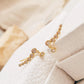 Pair of gold-plated bubble climber earrings with clear cubic zirconia stones arranged on soft white textured jewellery box.
