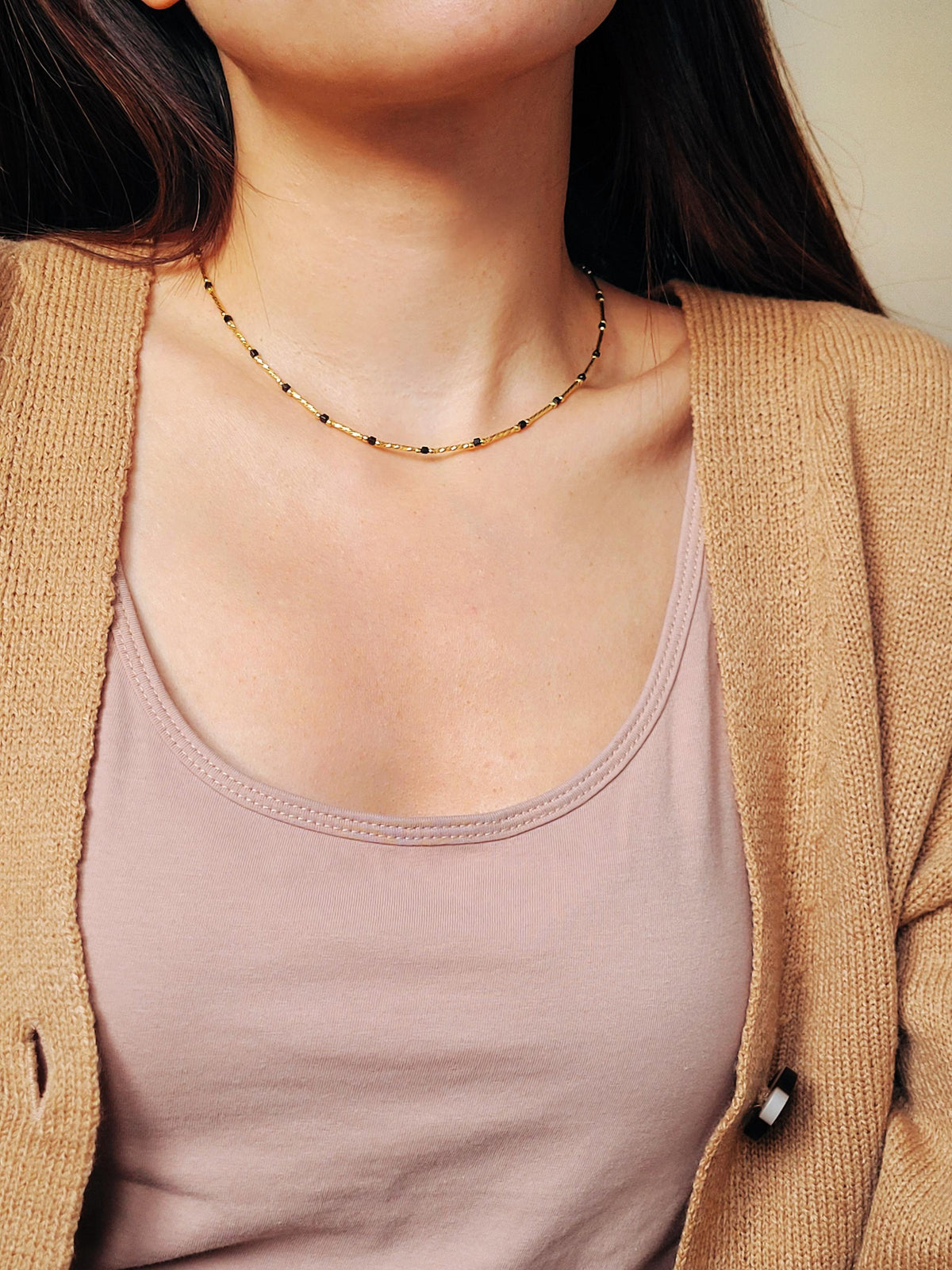 Close-up of a 22k gold vermeil choker necklace with black onyx beads worn around the neck. Crafted in 22k gold plated over sterling silver and natural gemstone. Perfect gift for her.