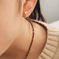 Side profile of a woman wearing a delicate gold bubble ear climber with a cream knitted jumper.