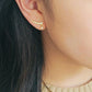 Close-up of a woman wearing a dainty gold bubble climber earring that follows the curve of her earlobe.