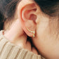 Close-up of a women's ear wearing gold crawler earrings with sparkling cubic zirconia stones, showcasing a minimalist and elegant ear climber design. Crafted in gold plated sterling silver.