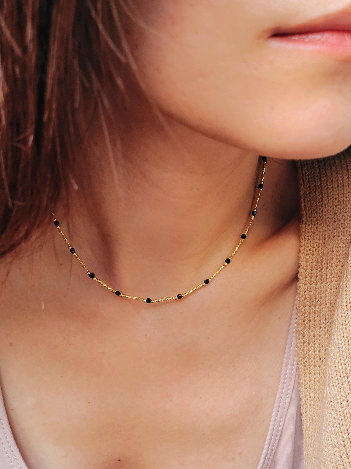 Close-up of a 22k gold vermeil choker necklace with black onyx beads worn around the neck. Crafted in 22k gold plated over sterling silver and natural gemstone. Perfect gift for her.